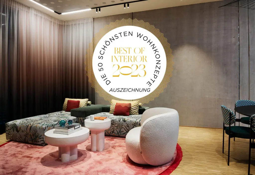 Sitzbereich mit rosa Teppich, weißem Sessel und grünem Sofa im Business Apartment mit Best-of-Interior-Siegel
