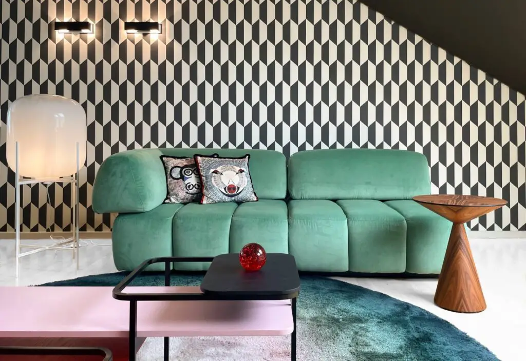 Grünes Sofa vor gemusterter Tapete im Showroom von RAUM+INHALT