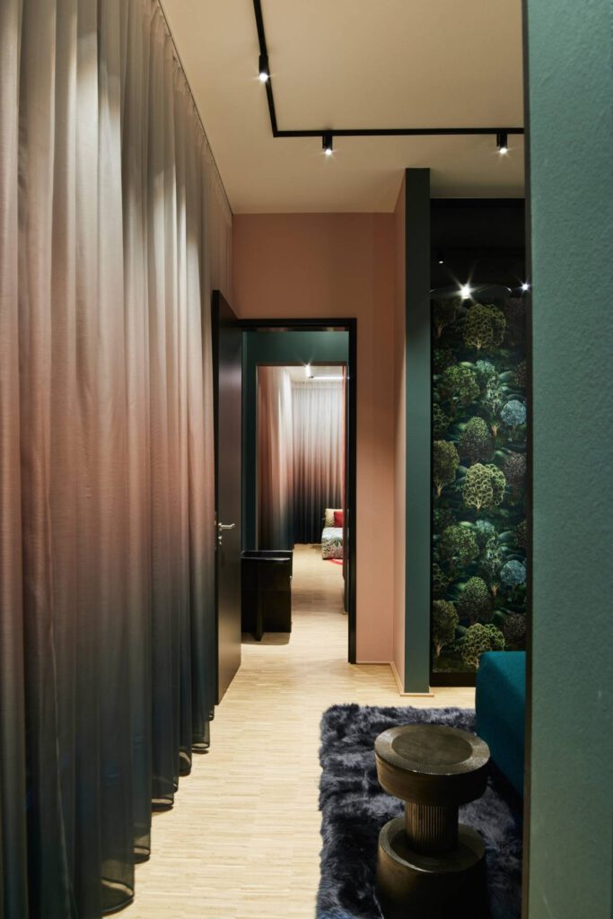 Blick durch Ombré-Vorhang und grüne Wände in den Schlafbereich des Business Apartments