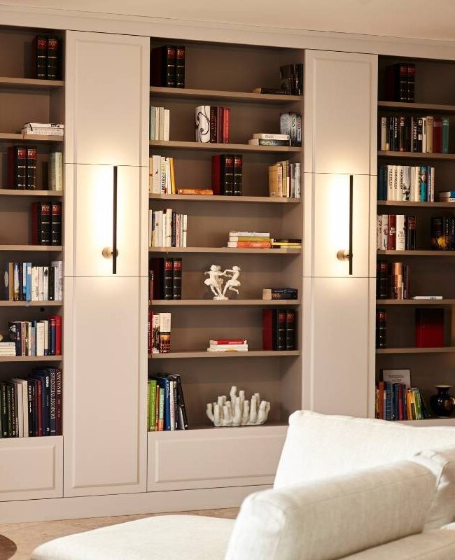 Raumhohes Bücherregal mit integrierten Leuchten hinter weißem Sofa in der Villa A