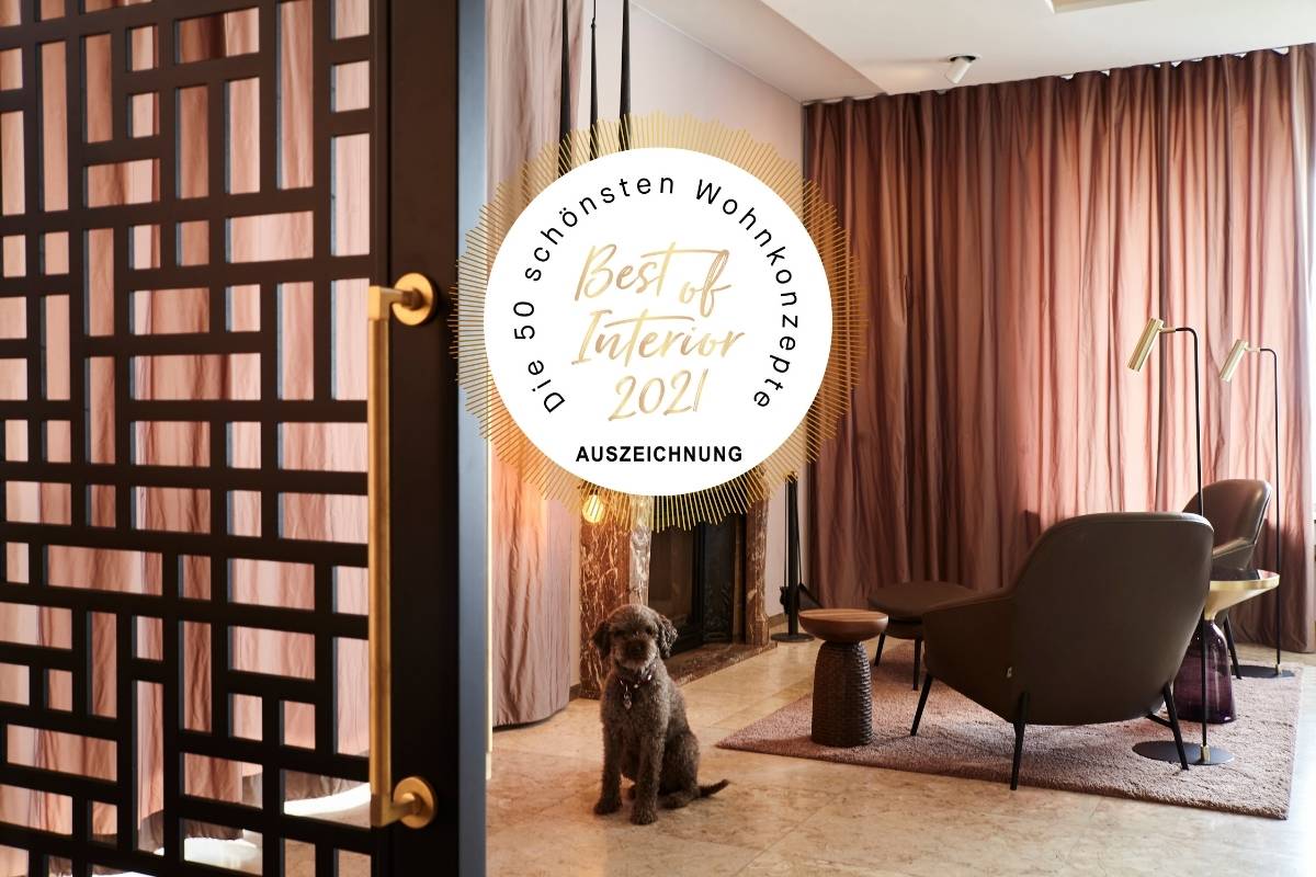 Wohnzimmer mit Ornament-Raumteiler, Lounge-Sessel, Hund und Siegel „Best of Interior 2021“, Villa A