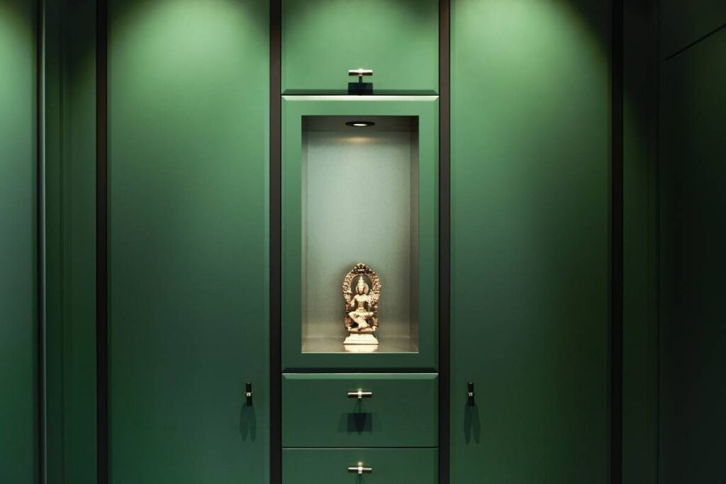 Dunkelgrüne Schrankwand mit beleuchteter Nische und goldener Figur in der Villa A