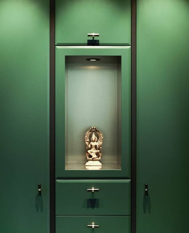 Dunkelgrüne Schrankwand mit beleuchteter Nische und goldener Figur in der Villa A