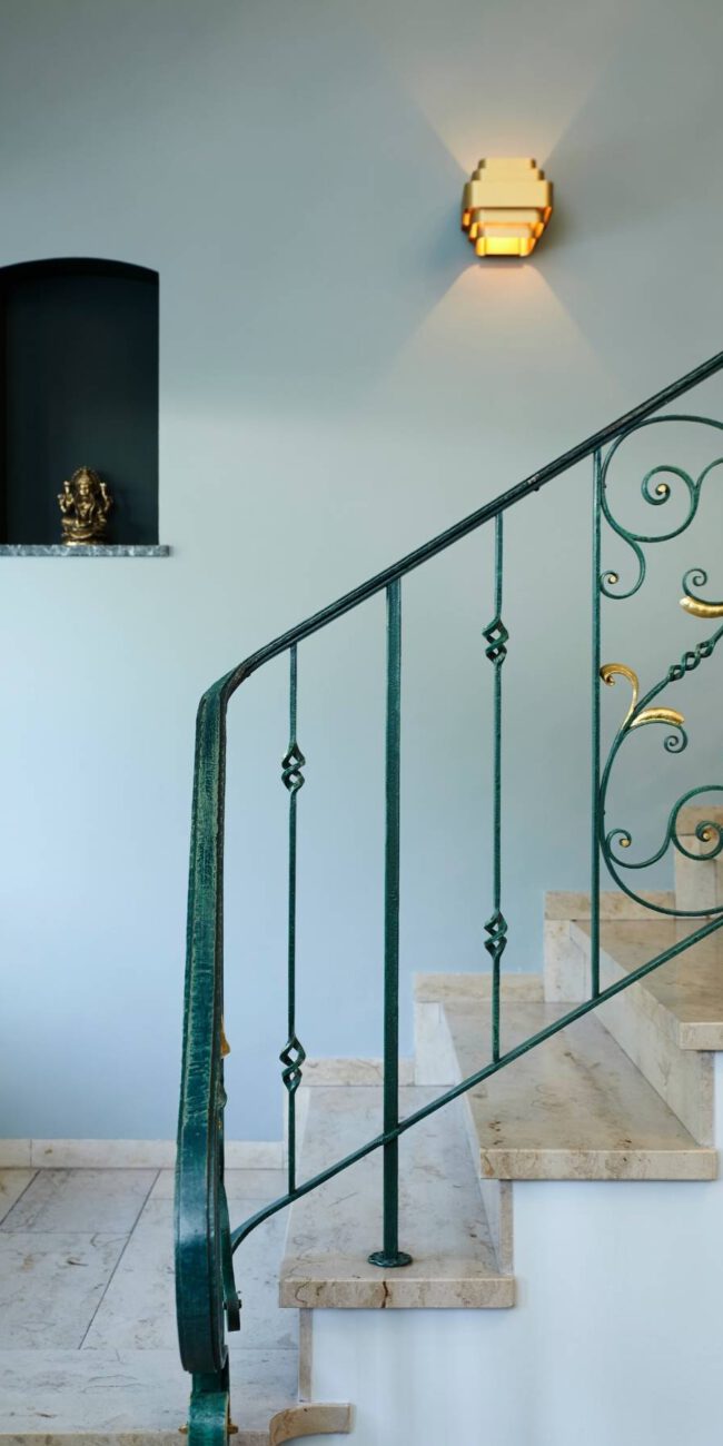 Treppe mit grünem, goldverziertem Schmiedegeländer und Wandnische in der Villa A