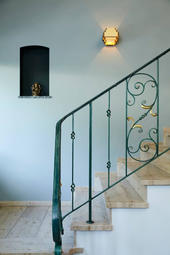 Treppe mit grünem, goldverziertem Schmiedegeländer und Wandnische in der Villa A