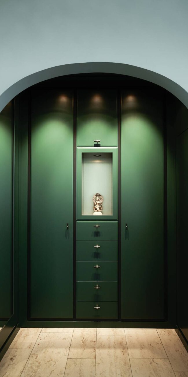 Grüner Einbauschrank mit beleuchteter Nische und Figur hinter Rundbogen in der Villa A