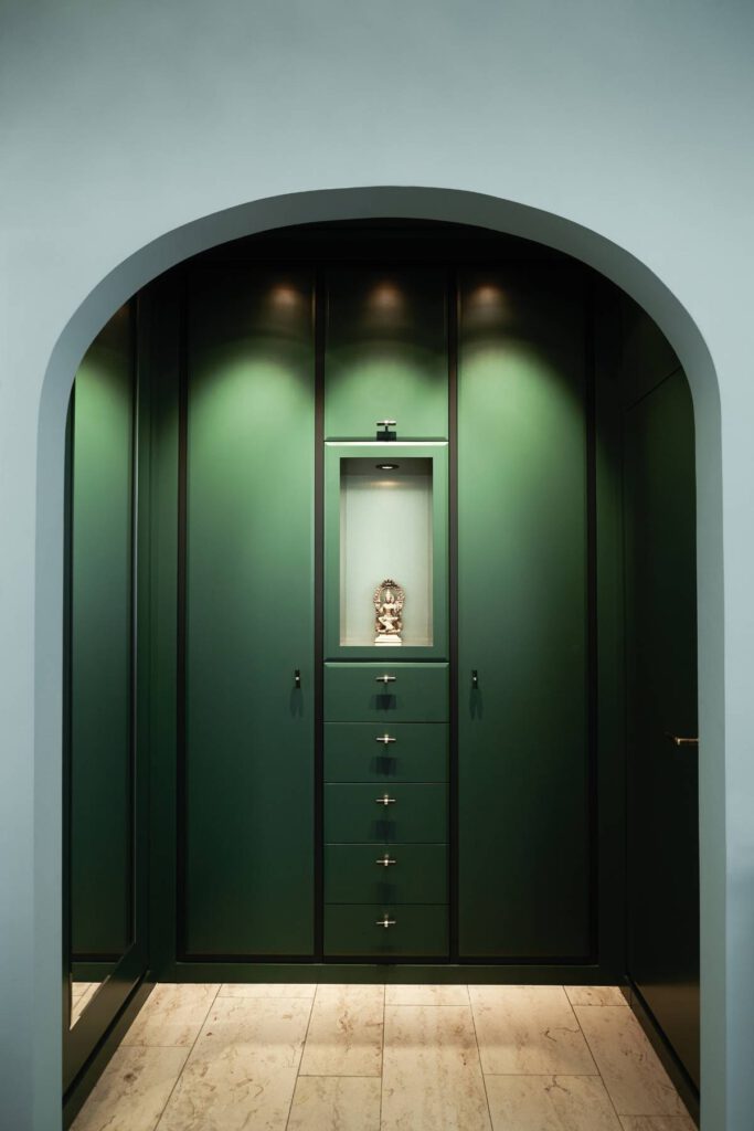 Grüner Einbauschrank mit beleuchteter Nische und Figur hinter Rundbogen in der Villa A
