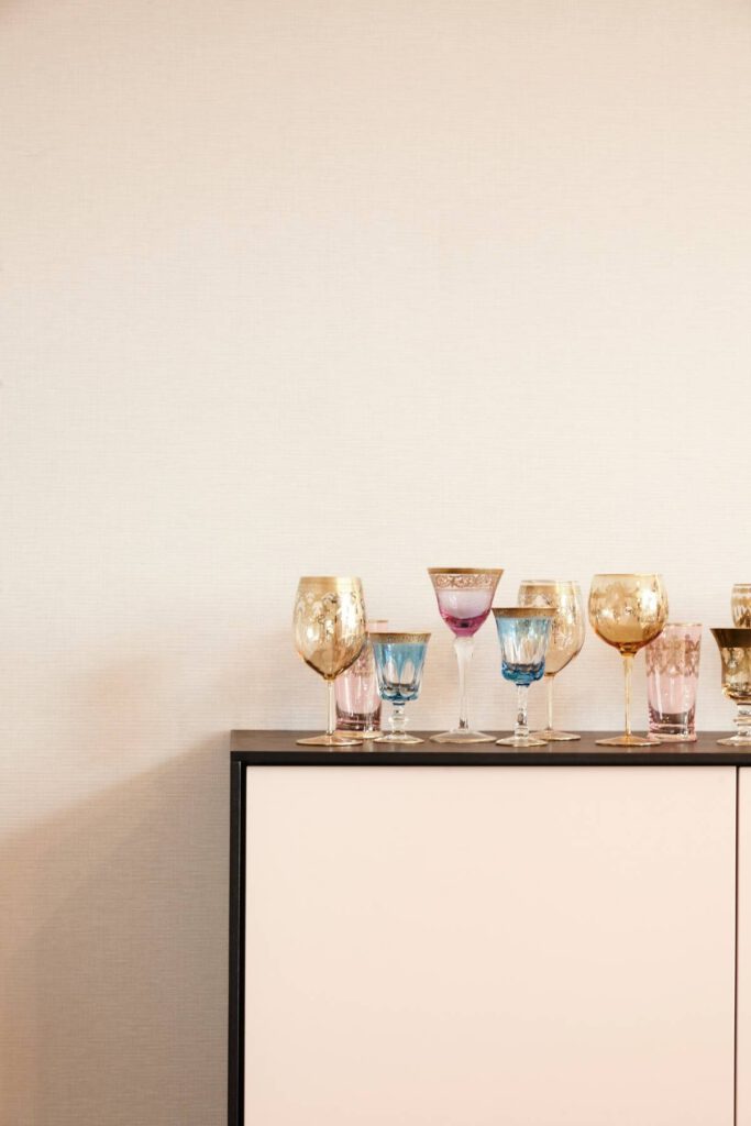 Bunte Kristallgläser auf Sideboard mit schwarzem Rahmen vor heller Wand, Villa A