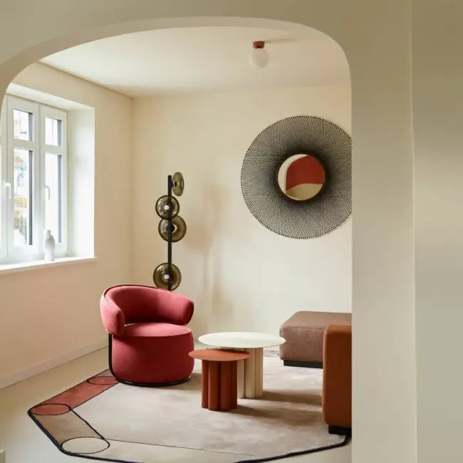 Blick durch Rundbogen auf roten Sessel, Spiegel und Stehleuchte in der Villa Haag