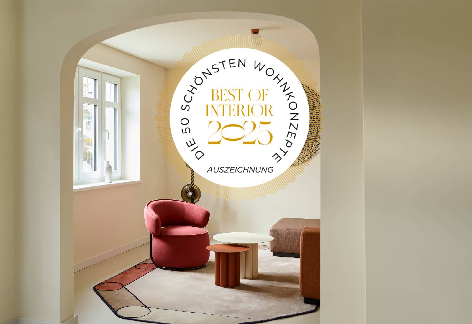 Leseecke mit rotem Sessel unter Rundbogen und Siegel „Best of Interior 2025“, Villa Haag