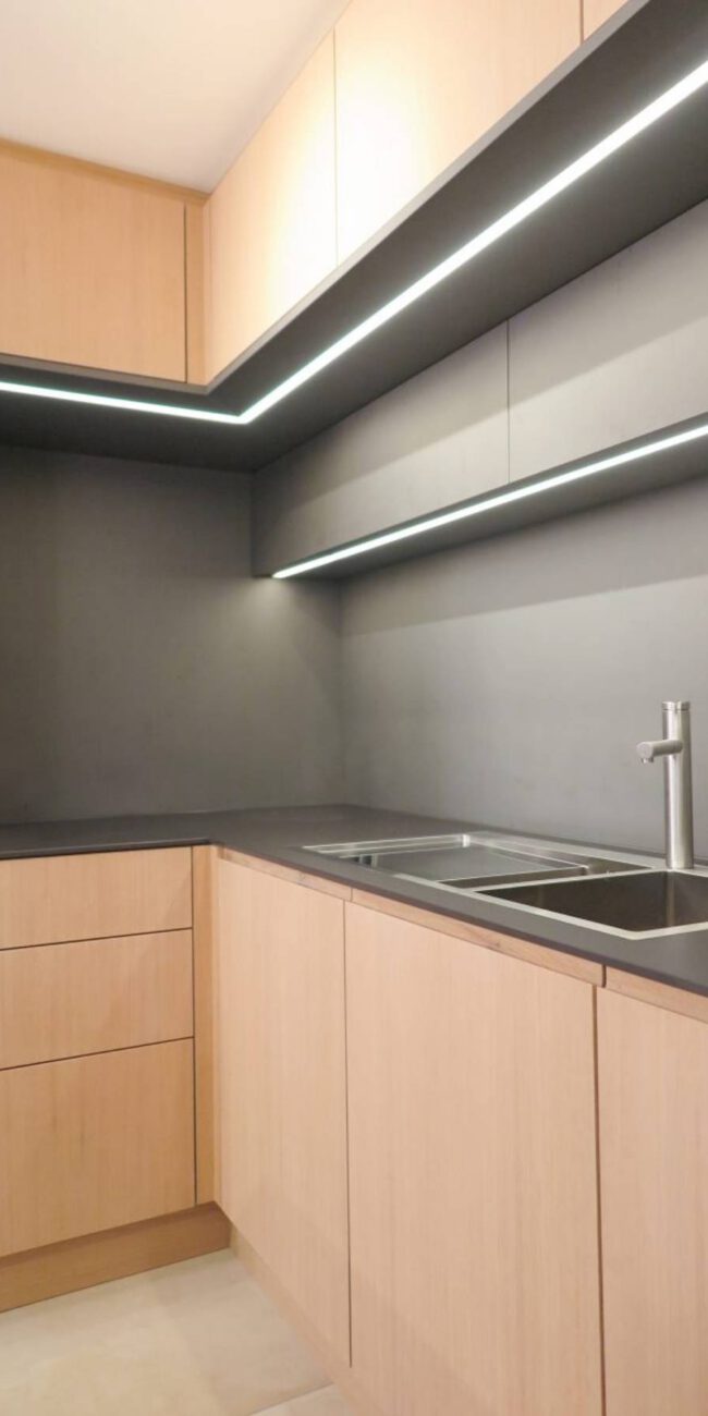 Küchenecke mit Eichenfronten, dunkler Rückwand und LED-Lichtleiste im Haus R in Kassel