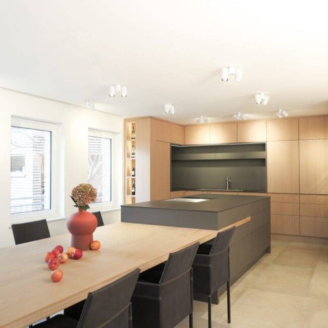 Langer Holztisch mit dunklen Stühlen vor Küche in Eichenholz im Haus R in Kassel