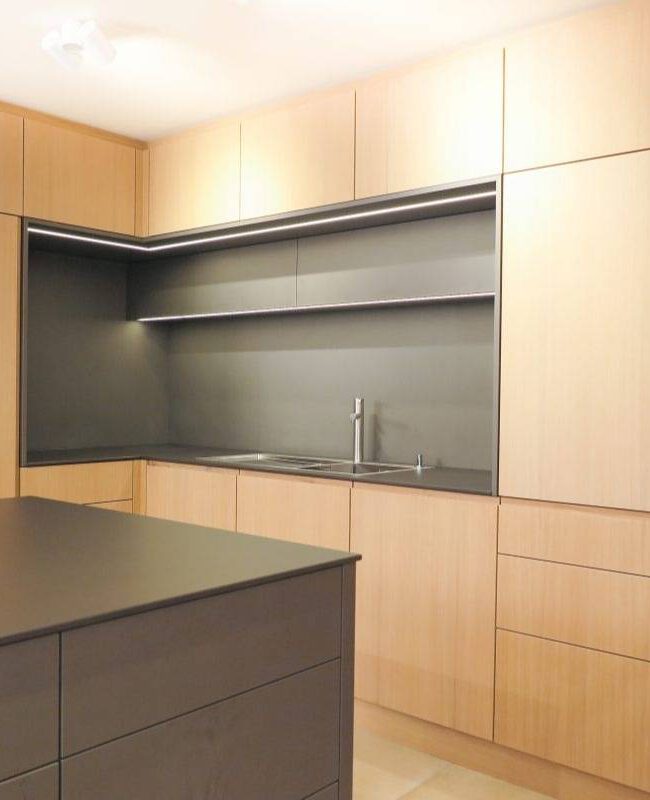 Küchenzeile mit Eichenfronten, dunkler Arbeitsplatte und beleuchteter Nische im Haus R in Kassel