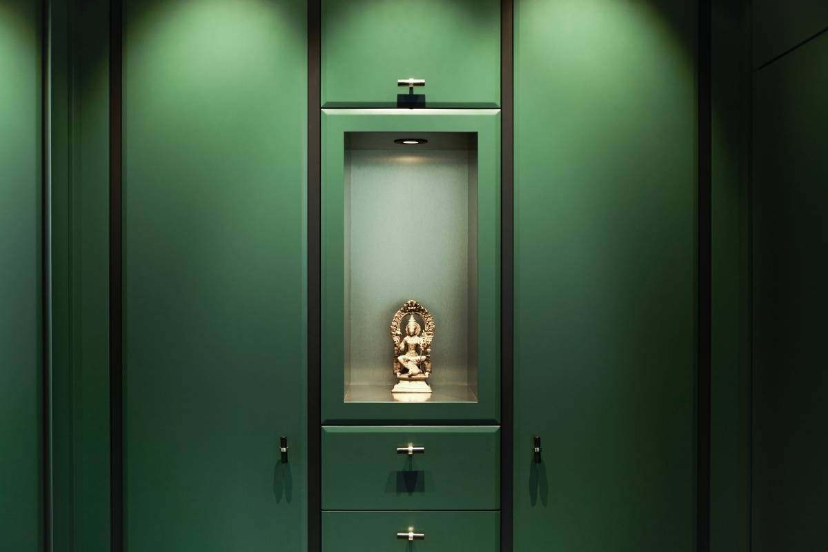 Dunkelgrüne Schrankwand mit beleuchteter Nische und Skulptur in der Villa A