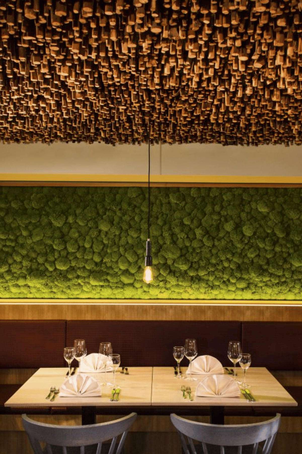 Restauranttisch unter Holzdecke vor begrünter Wand mit Pendelleuchte im Taufstein Restaurant II
