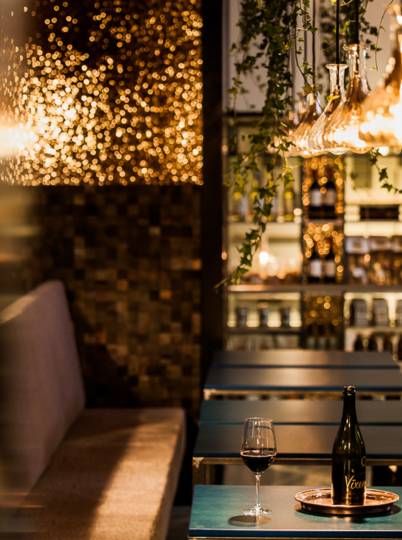 Bar mit Holzmosaik, Pflanzen und Weinregal im Brunos Bistro
