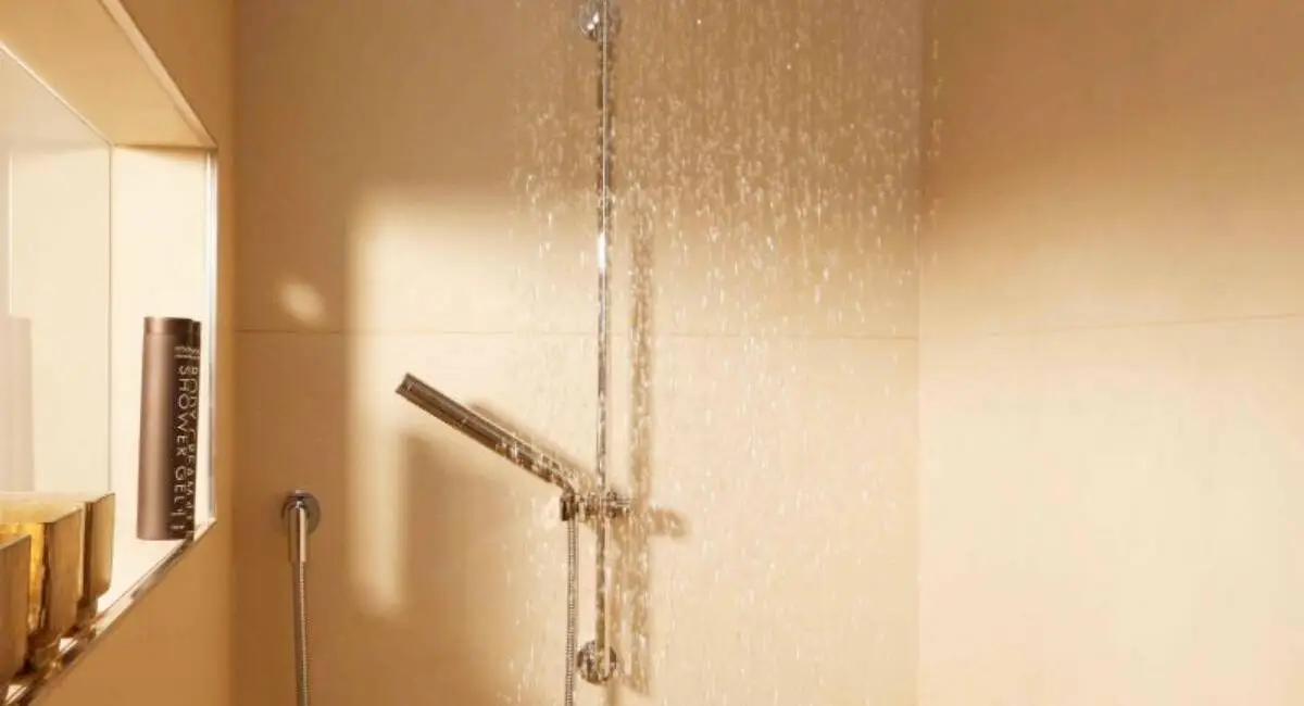 Regendusche mit goldschimmernden Mosaikfliesen und Wandnische im Bad der Suite A