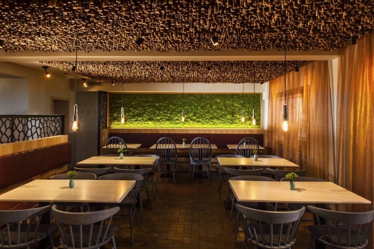 Gastraum mit Holzstab-Decke, Mooswand und hellen Holztischen im Taufstein Restaurant II