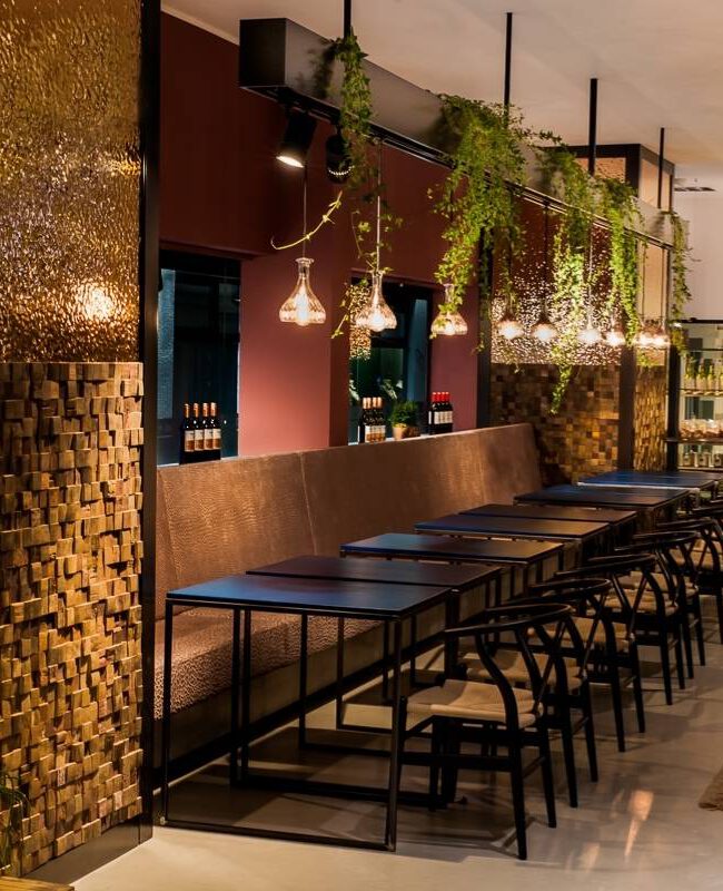 Sitzbank mit Holzmosaikwand, Teppichen und Blick ins Weinregal in Brunos Bistro