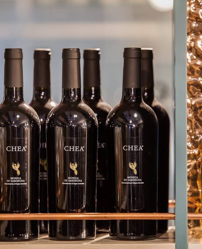 Rotweinflaschen und Roséflasche vor gehämmerter Kupferwand im Regal von Brunos Bistro