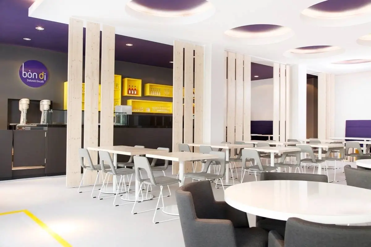 Gastraum mit Holzlamellen, grauen Stühlen und violetten Deckenkreisen im Eiscafé Bon’di
