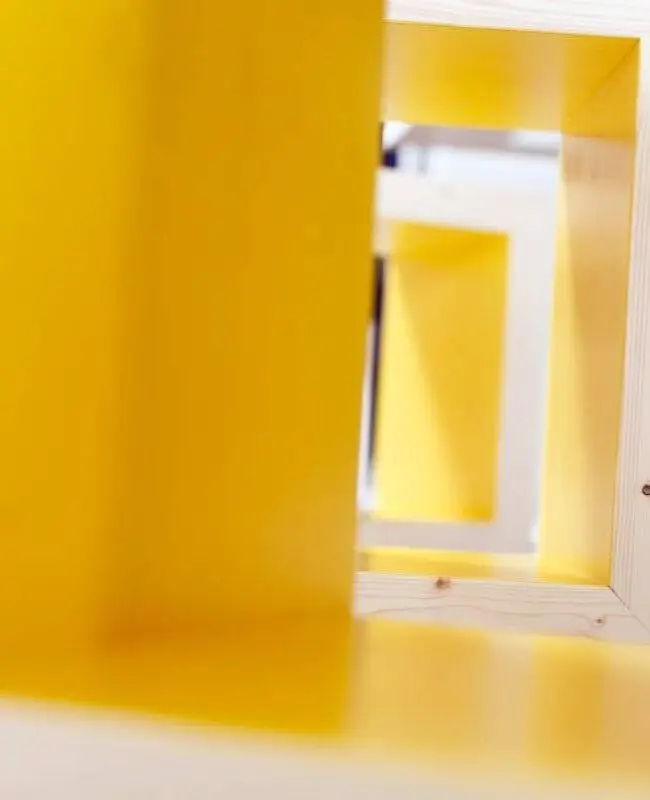 Detail eines Holzhockers mit leuchtend gelber Innenfläche im Eiscafé Bon’di