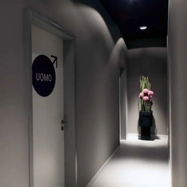 Dunkler Flur zu den Toiletten mit Pflanzenarrangement am Ende im Eiscafé Bon’di