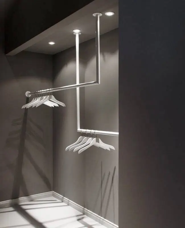 Garderobe mit weißen Kleiderbügeln an Metallstange vor dunkelgrauer Wand im Eiscafé Bon’di