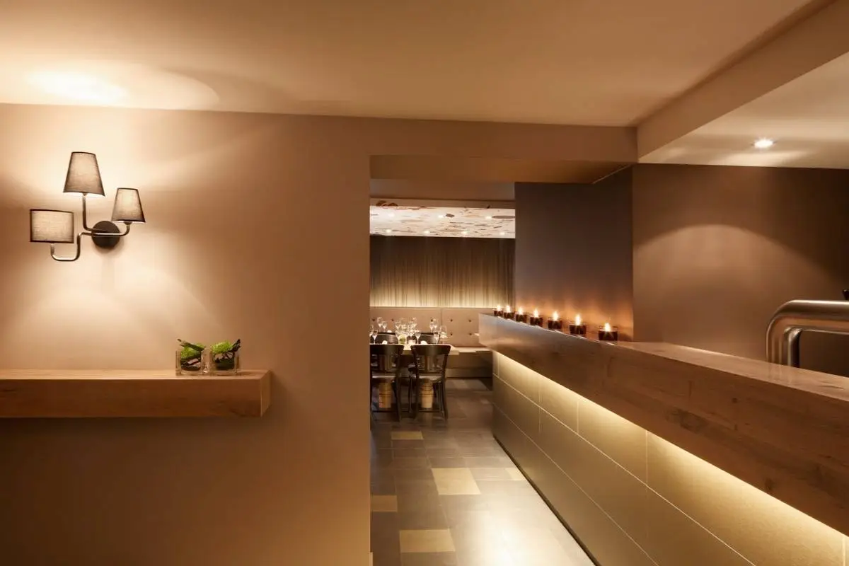 Eingangsbereich mit Wandleuchte, beleuchteter Theke und Blick in den Gastraum, Hotel Taufstein Restaurant I