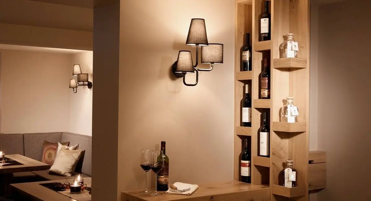 Weinregal aus Eiche mit Wandleuchte und Rotweinflasche auf Holzablage, Hotel Taufstein Restaurant I