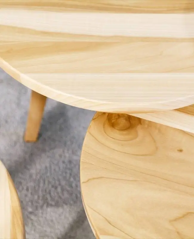 Detail runder Beistelltische aus hellem Holz auf grauem Teppich, Praxis Winner