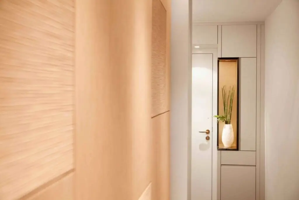 Strukturierte Holzwand und Flur mit beleuchteter Nische und Pflanze in der Suite A