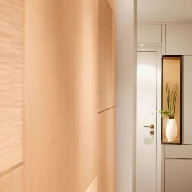 Strukturierte Holzwand und Flur mit beleuchteter Nische und Pflanze in der Suite A