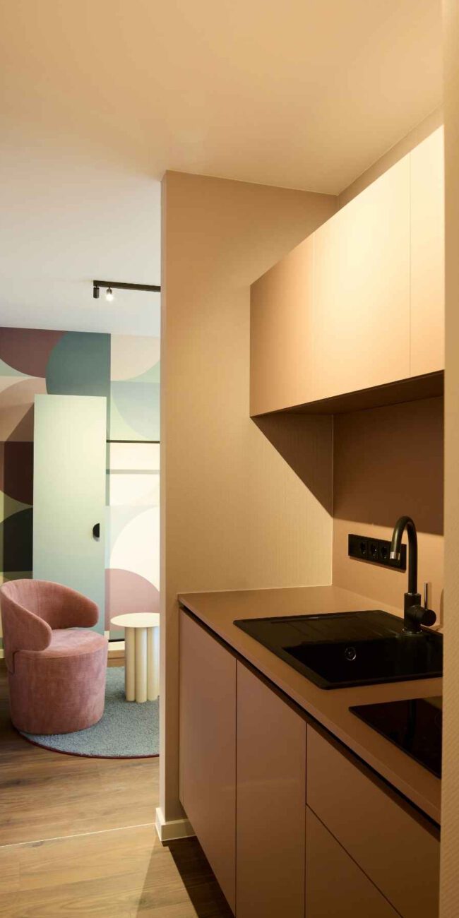 Pantryküche in Beige mit schwarzer Spüle und Blick ins Zimmer, Gästehaus 2, Haus der Standesbeamten