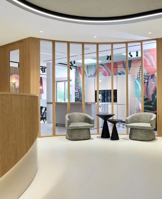 Empfang mit Holzlamellen-Tresen, Lichtband und Wartesesseln hinter Glaswand bei Alt & Partner