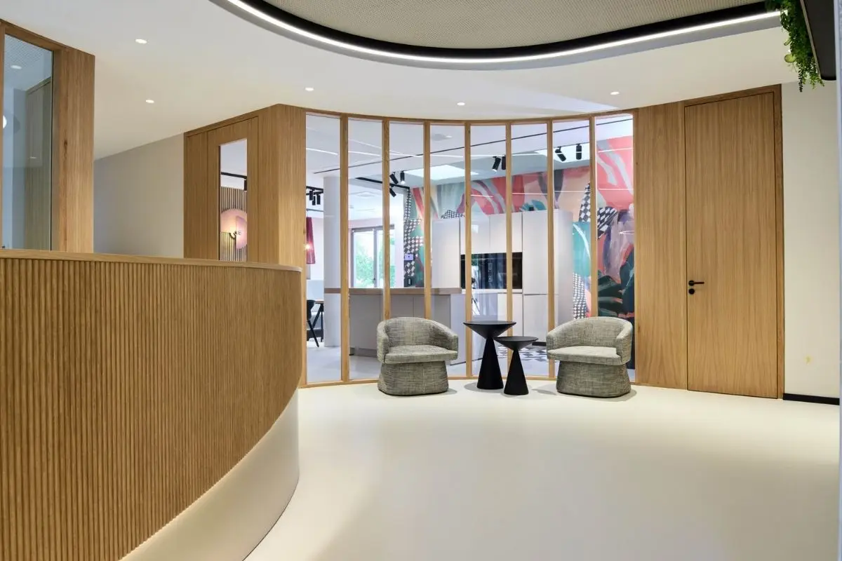 Empfang mit Holzlamellen-Tresen, Lichtband und Wartesesseln hinter Glaswand bei Alt & Partner