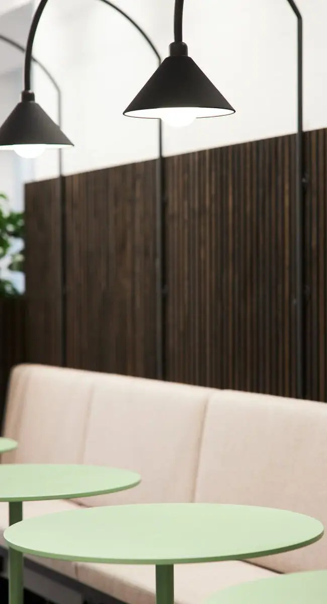 Schwarze Bogenleuchten über rosa Bank und mintgrünen Tischen, Lobby im Haus der Standesbeamten