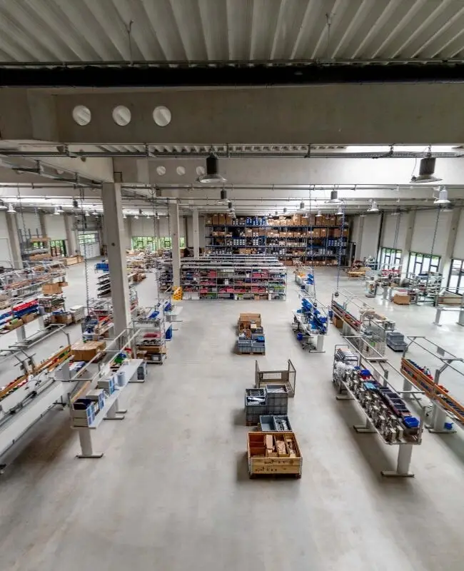 Produktionshalle mit Montagetischen und Regalen unter Hallendach bei Belfox