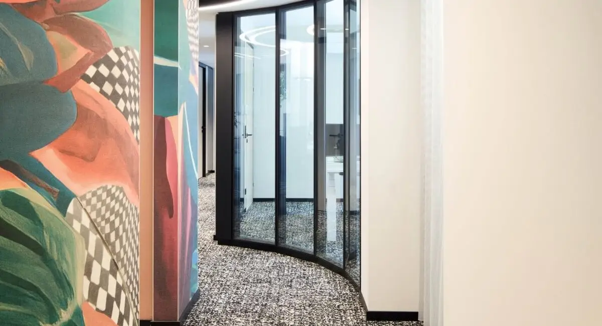 Geschwungene Wand mit bunter Blättergrafik und Lichtband im Flur bei Alt & Partner