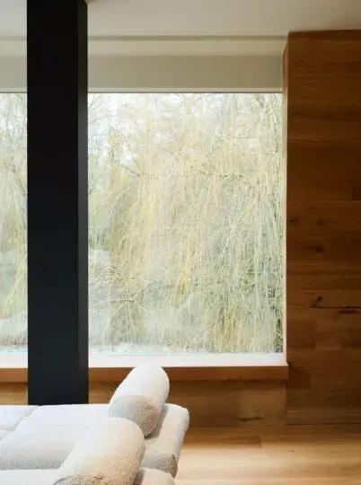 Ruhebereich mit Holzverkleidung, Liege und Blick ins Grüne in der Private Wellness Suite