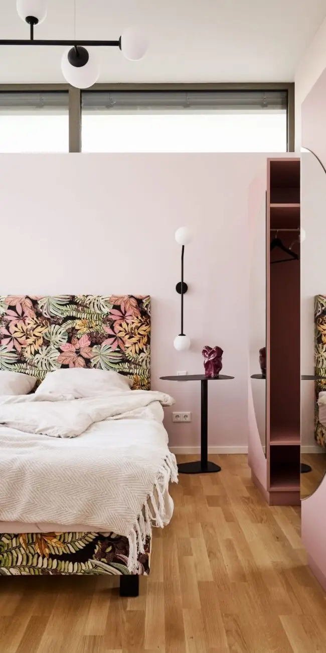 Doppelbett mit Blumenkopfteil, schwarzer Wandleuchte und Garderobennische in der Ferienwohnung