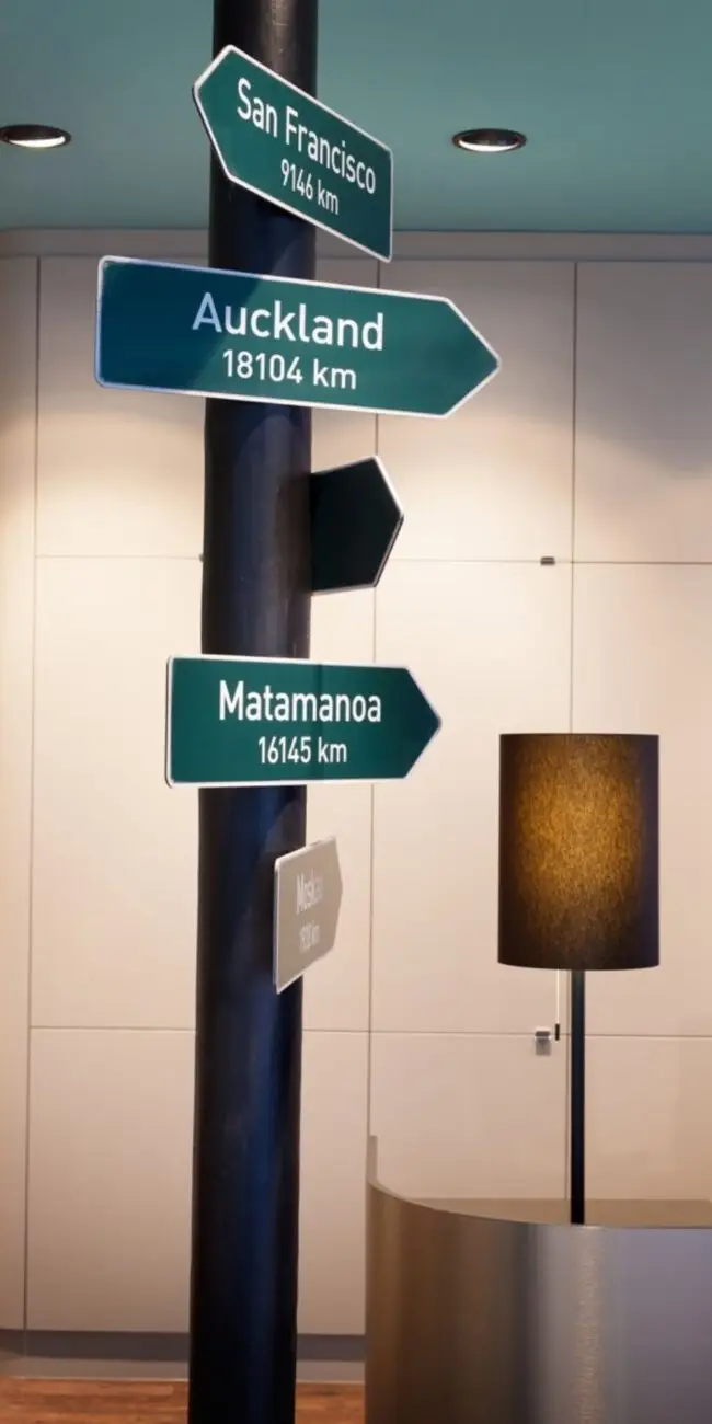 Säule mit Wegweisern nach Auckland und San Francisco bei Merican Reisebüros