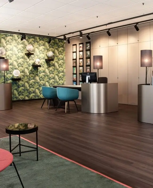 Reisebüro mit Palmentapete, Globen, rosa Loungesesseln und Beratungstresen bei Merican Reisebüros