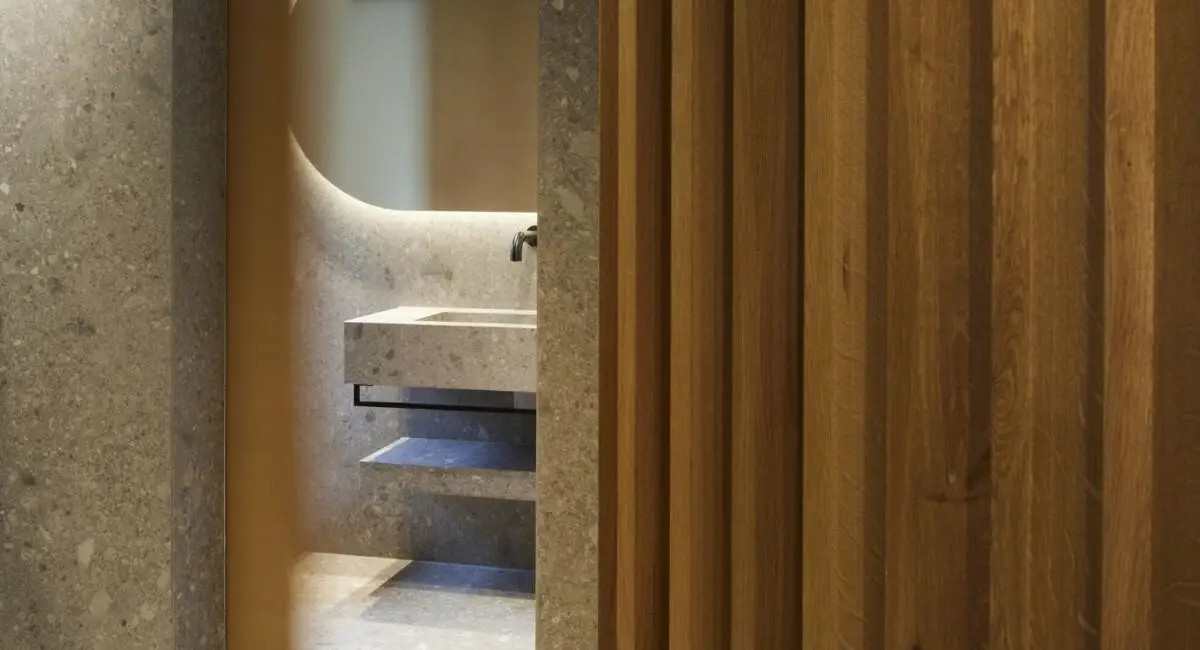 Blick an Holzlamellen vorbei ins Bad mit Steinwaschtisch, Private Wellness Suite