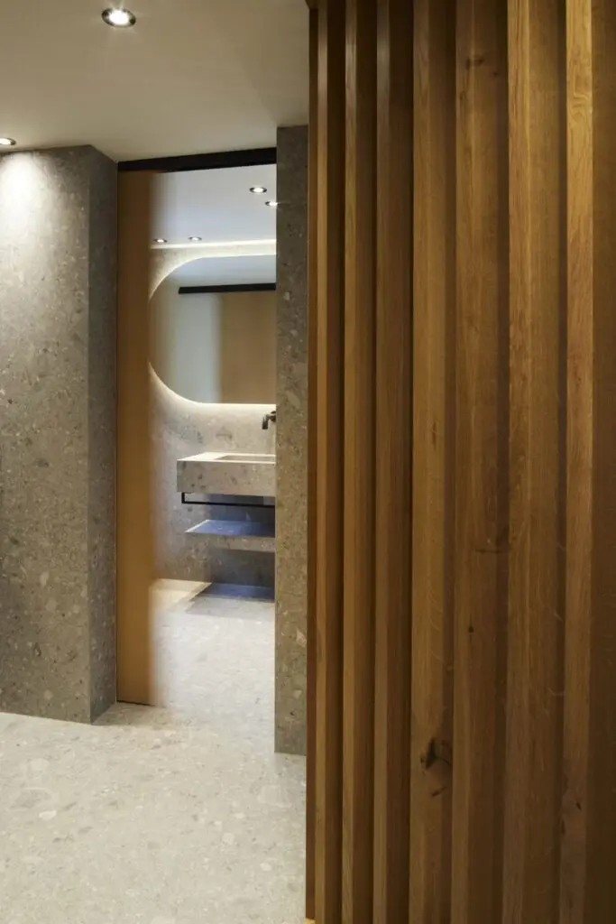 Blick an Holzlamellen vorbei ins Bad mit Steinwaschtisch, Private Wellness Suite