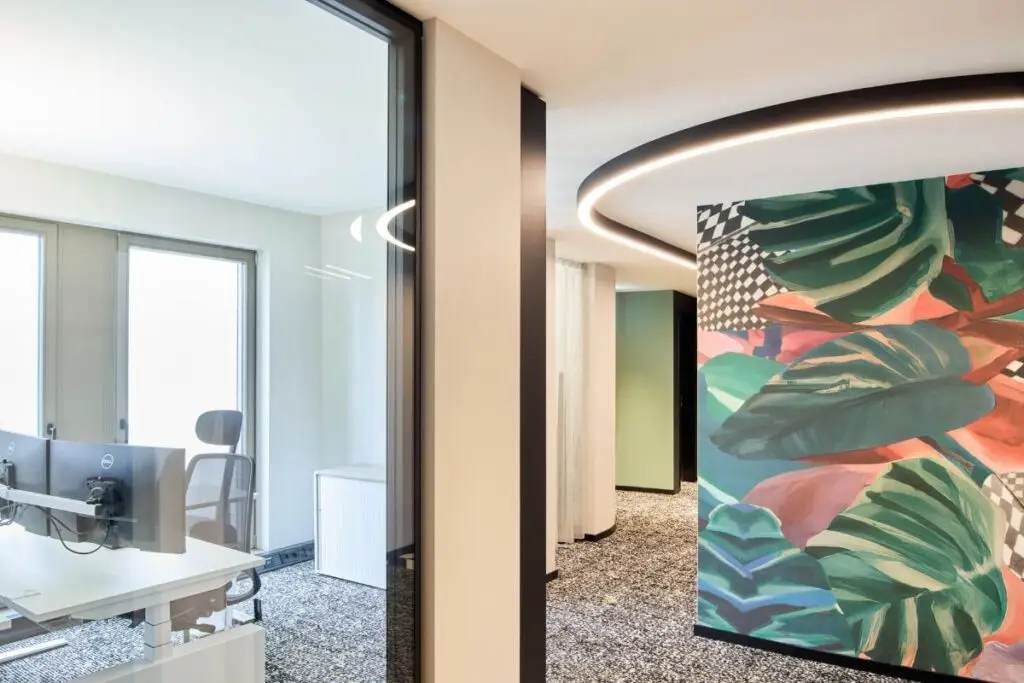 Blick in ein Büro mit Schreibtisch neben bunter Grafikwand bei Alt & Partner