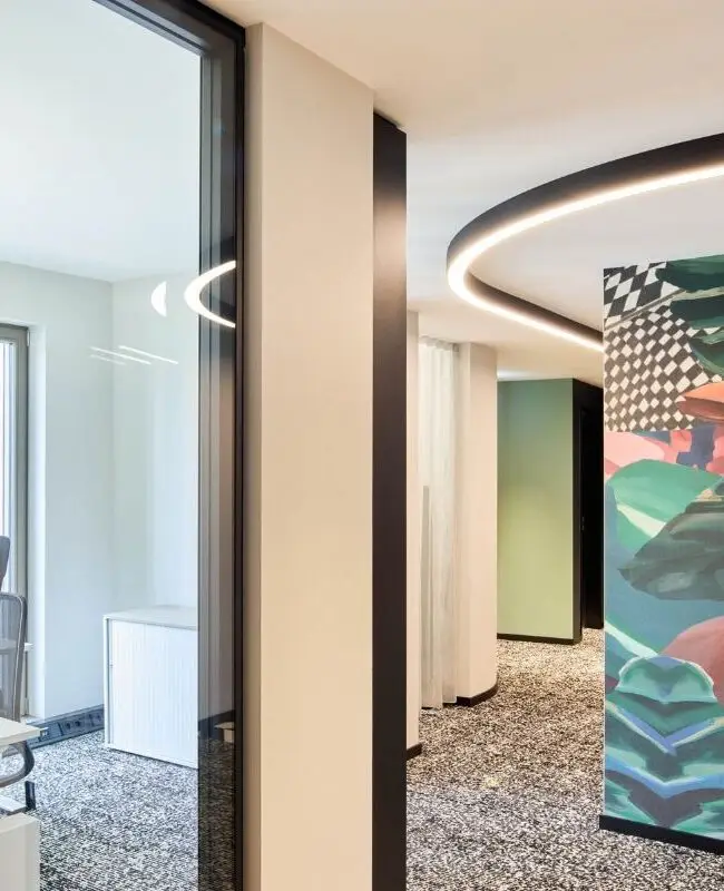 Blick in ein Büro mit Schreibtisch neben bunter Grafikwand bei Alt & Partner