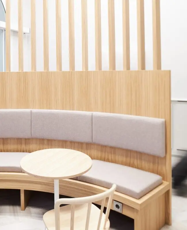 Halbrunde Bank mit Bistrotischen und Eichenlamellen, Reisender im Hintergrund, Lobby im Haus der Standesbeamten