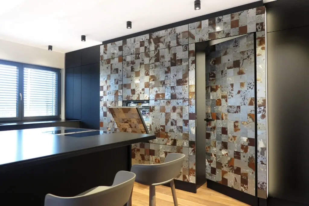Hochschrankwand mit Fliesenmosaik und offener Klappe neben Kochinsel im Haus S