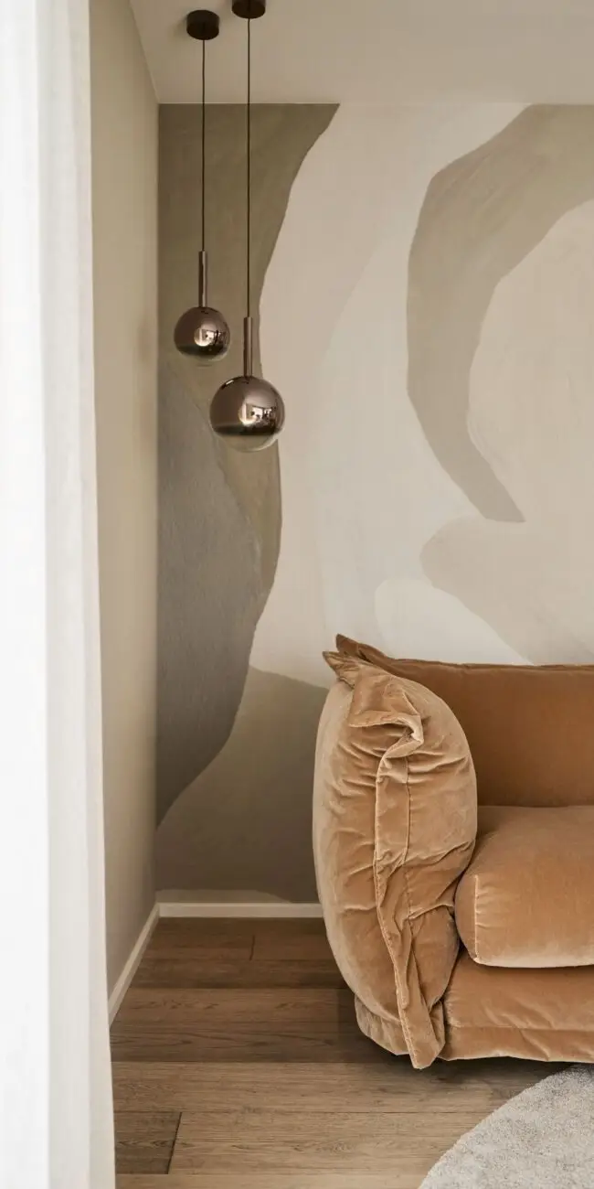 Samtsofa in Cognac vor Wandmalerei mit Pendelleuchten aus Rauchglas im Haus R in Fulda